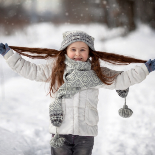 A young girl smiling and showcasing a stylish winter hairstyle for kids.