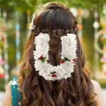 Girl smiling with low bun hairstyle decorated with gajra flowers.